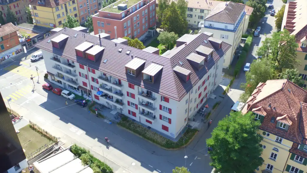 Mehrfamilienhaus nach Sanierung aus der Vogelperspektive mit Balkonen und ausgebautem Dachgeschoss in urbanem Quartier.