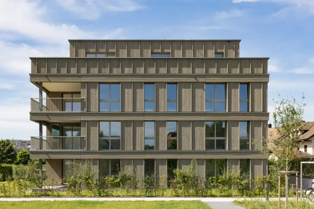 Die natürliche Holzfassade verleiht dem Ensemble eine warme Ausstrahlung und fügt sich harmonisch in die grüne Umgebung ein.